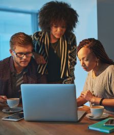 Man and two women looking at a laptop